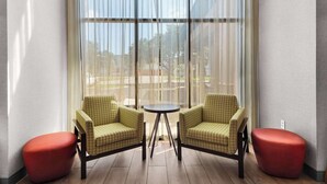 Una habitación con dos sillones estampados, una mesita redonda pequeña y dos otomanes rojos.