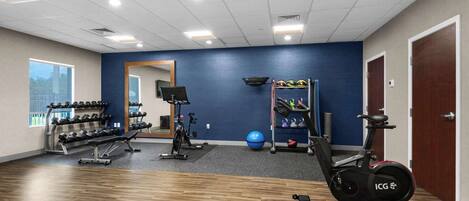 A gym with exercise equipment, a mirror, and a window.