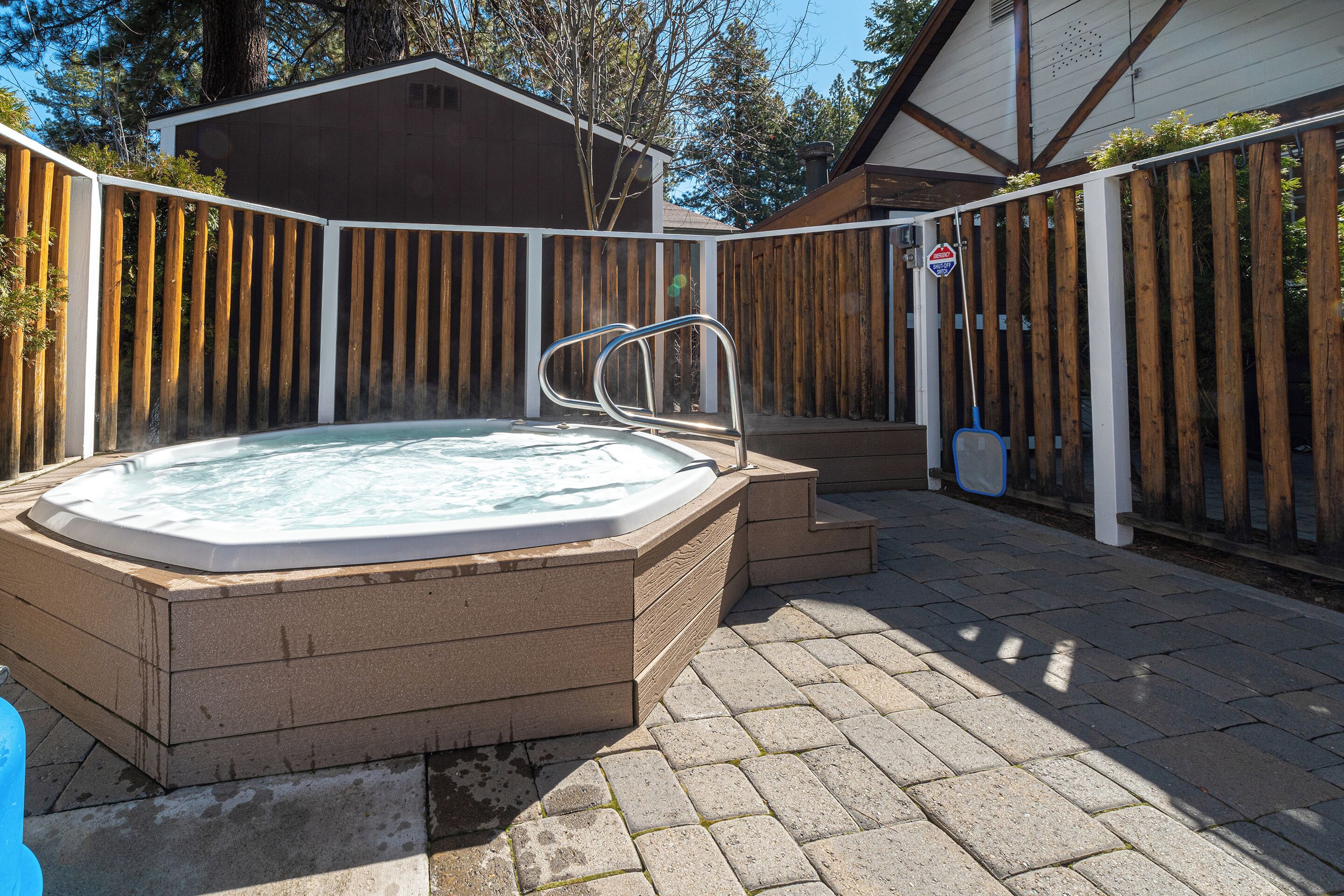 A hot tub in a backyard with a wooden fence and steps leading up to it.