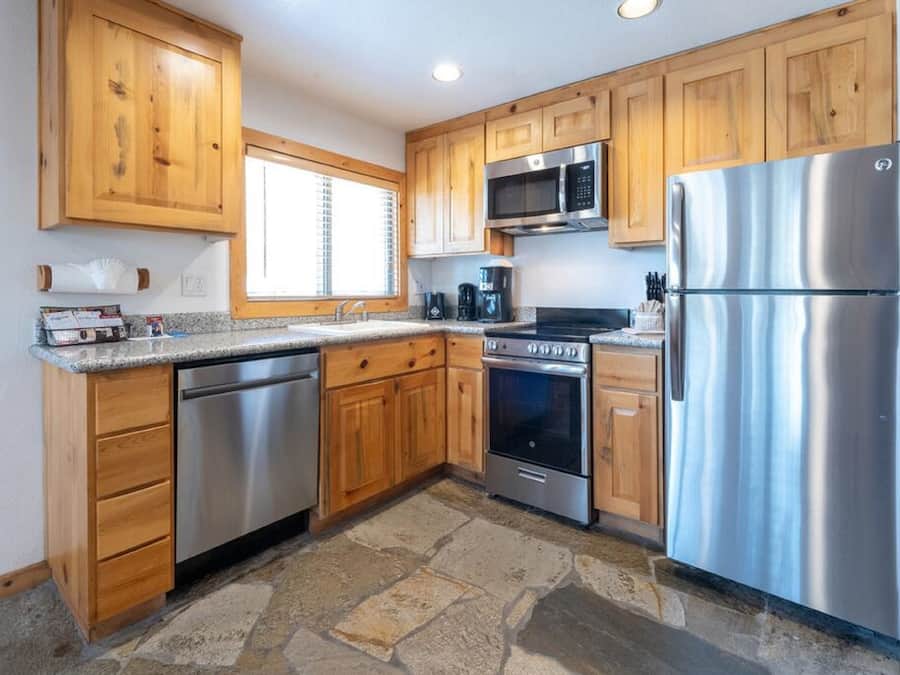 A kitchen with wooden cabinets, a stainless steel refrigerator, a microwave, an oven, and a dishwasher.