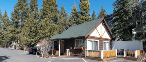 A small lodge with a green roof, wooden exterior, and a fenced porch.