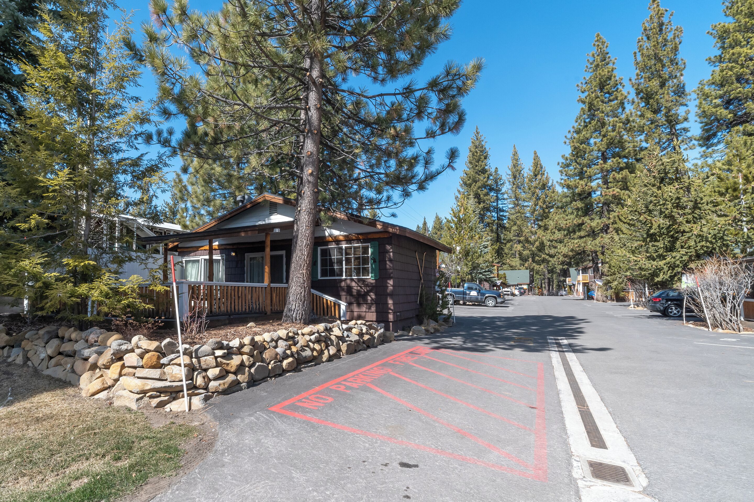 A lodge with a stone wall and a clear driveway.