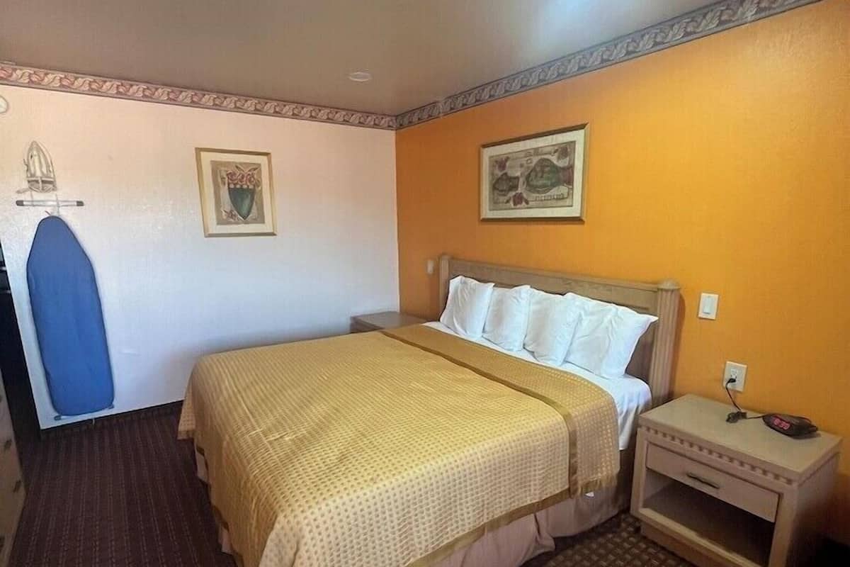 Une chambre d’hôtel avec un lit, une table de chevet et une horloge fixée au mur.
