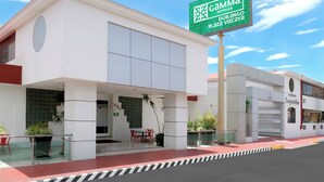 Un hotel moderno con un llamativo letrero verde, un acceso cubierto y fachada de vidrio.