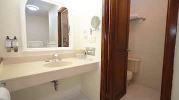 Un baño con lavamanos doble, un espejo, inodoro y mampara de ducha.