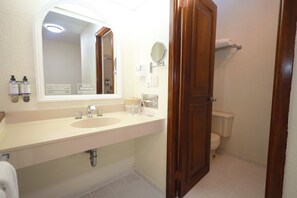 Un baño con lavamanos doble, un espejo, inodoro y mampara de ducha.