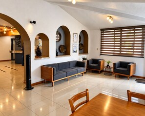 A spacious lobby with a modern sofa, armchairs, a wooden table, and a reception desk. - Gamma Durango Plaza Vizcaya (Durango)
