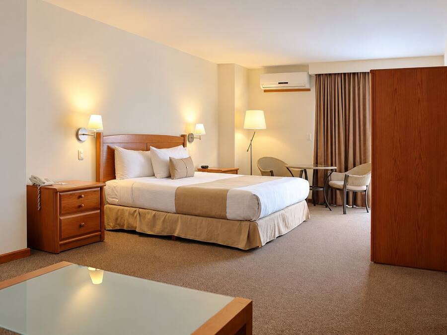 Ein Hotelzimmer mit Bett, Nachttischen, Schreibtisch und Stuhl.