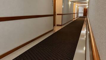 Un pasillo de hotel con alfombra estampada, paredes blancas y molduras de madera.
