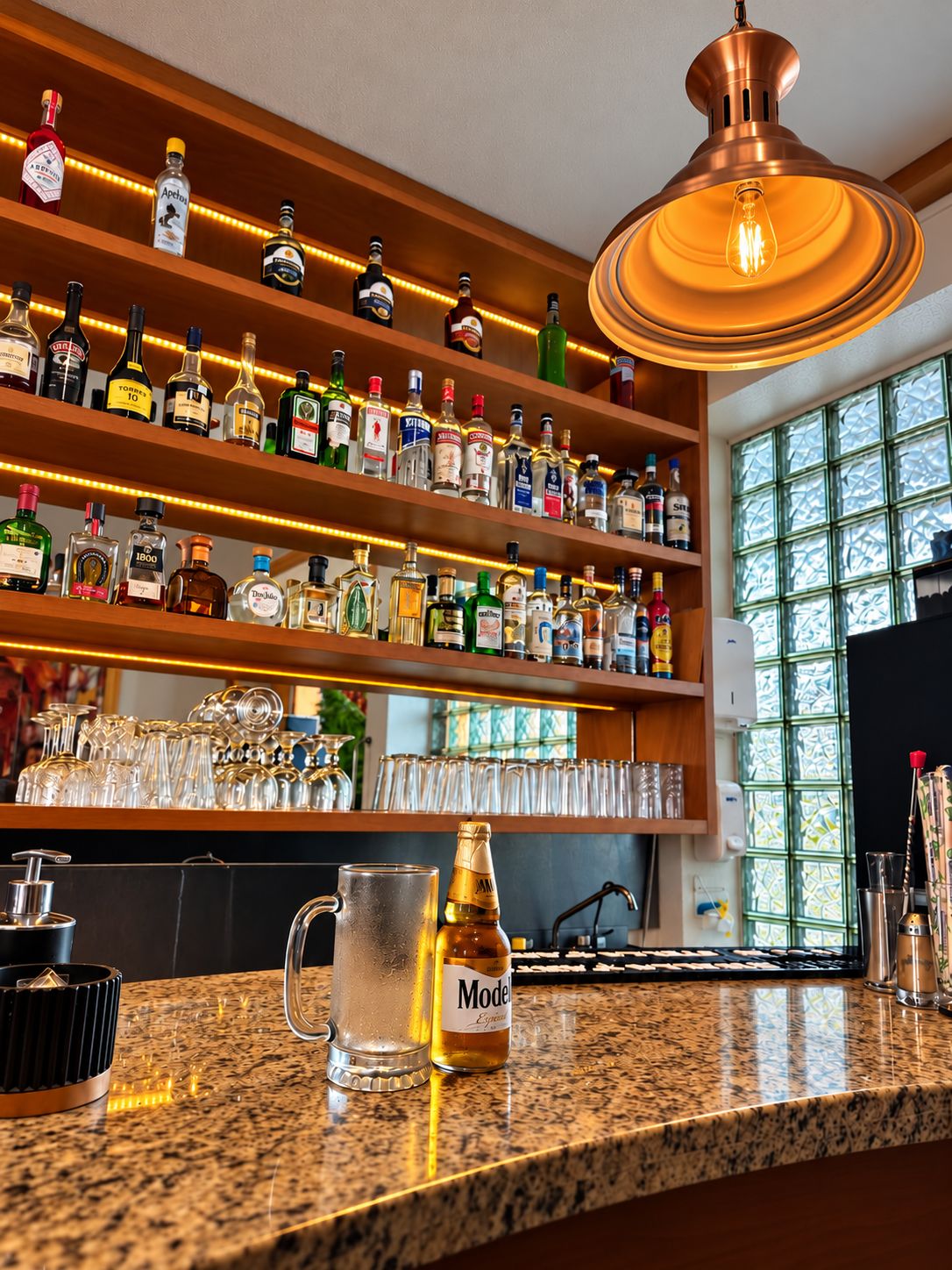 A bar area with shelves of liquor bottles, a copper pendant light, and a granite countertop with a bottle of Modena wine.