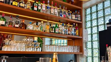A bar area with shelves of liquor bottles, a copper pendant light, and a granite countertop with a bottle of Modena wine.