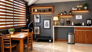 Una cocina moderna con comedor, que incluye una mesa y sillas de madera, una estación de café y un cubo de basura.