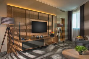 Uma sala de estar moderna com uma grande televisão de tela plana, painéis de madeira, um sofá, uma mesa de centro e um vaso com planta.