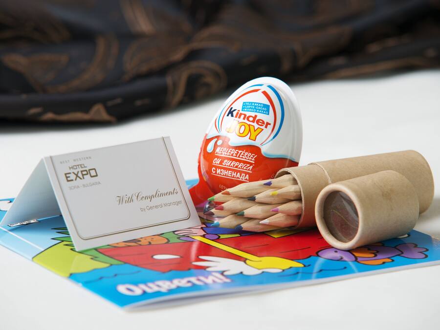 A Kinder Joy egg, a business card, and a colorful brochure on a white surface.