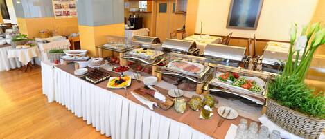 A buffet setup with various food stations, including fruits, meats, and salads.