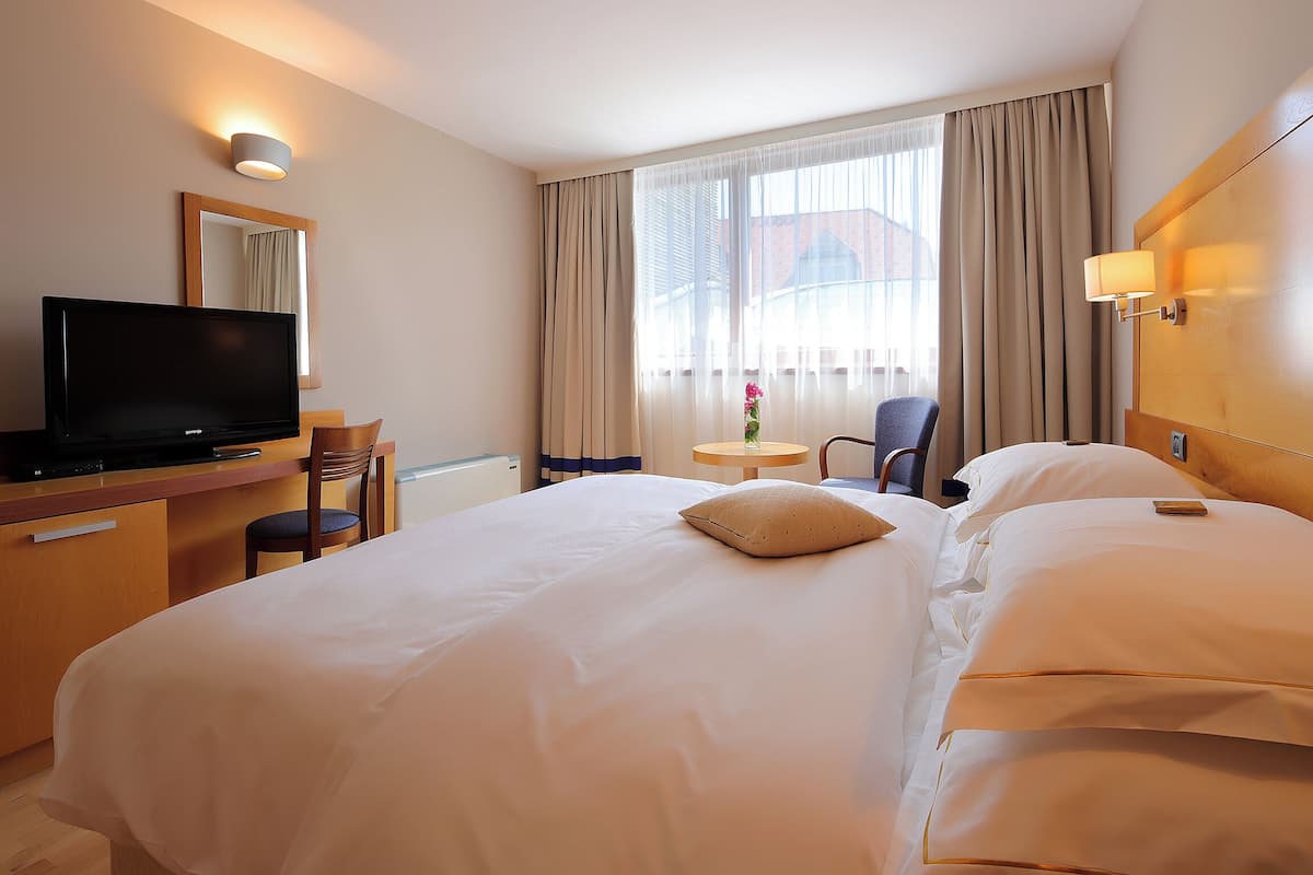 A hotel room with a bed, a television, a desk, and a chair.