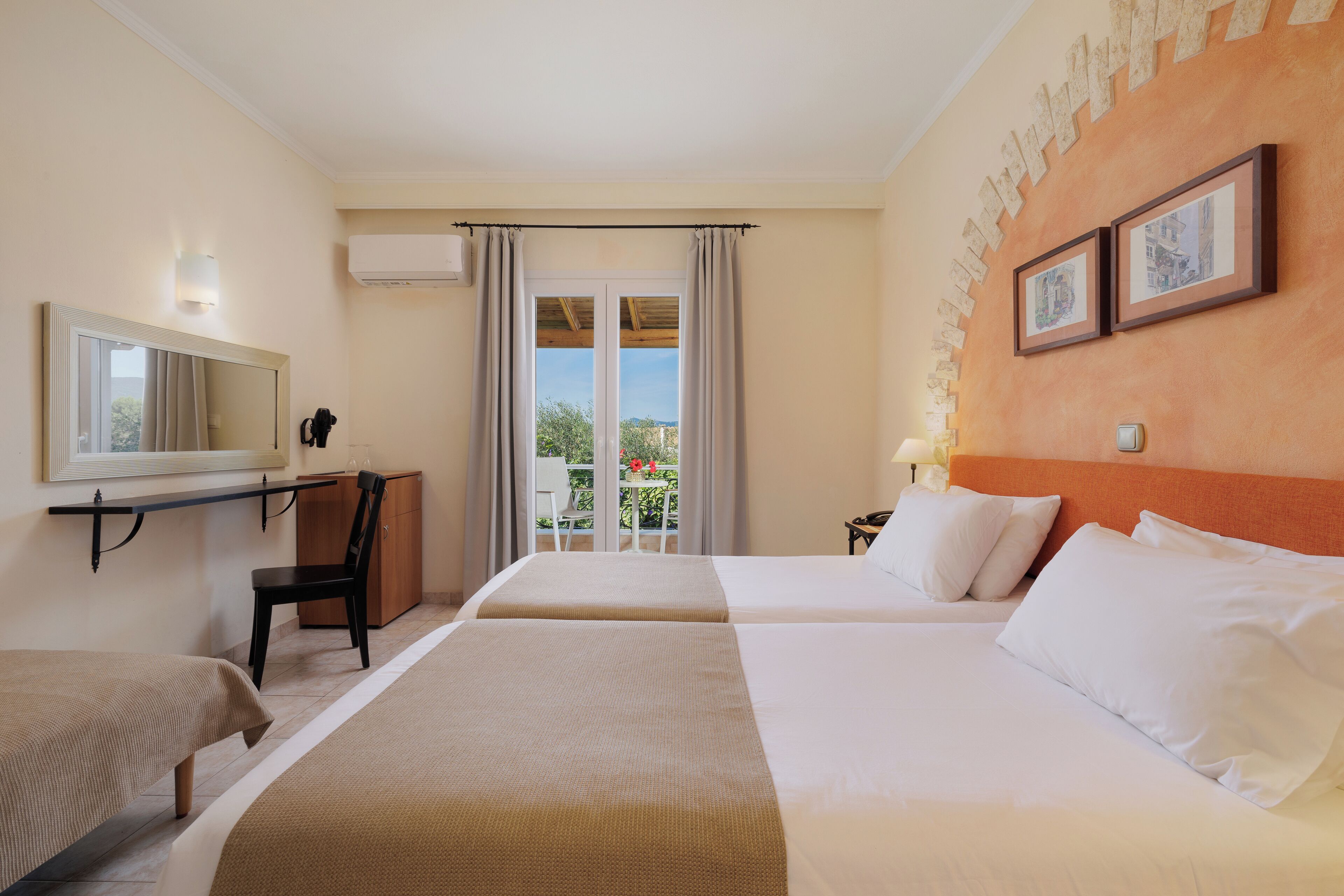 A hotel room with two beds, a desk, a chair, a mirror, and a balcony with a view.