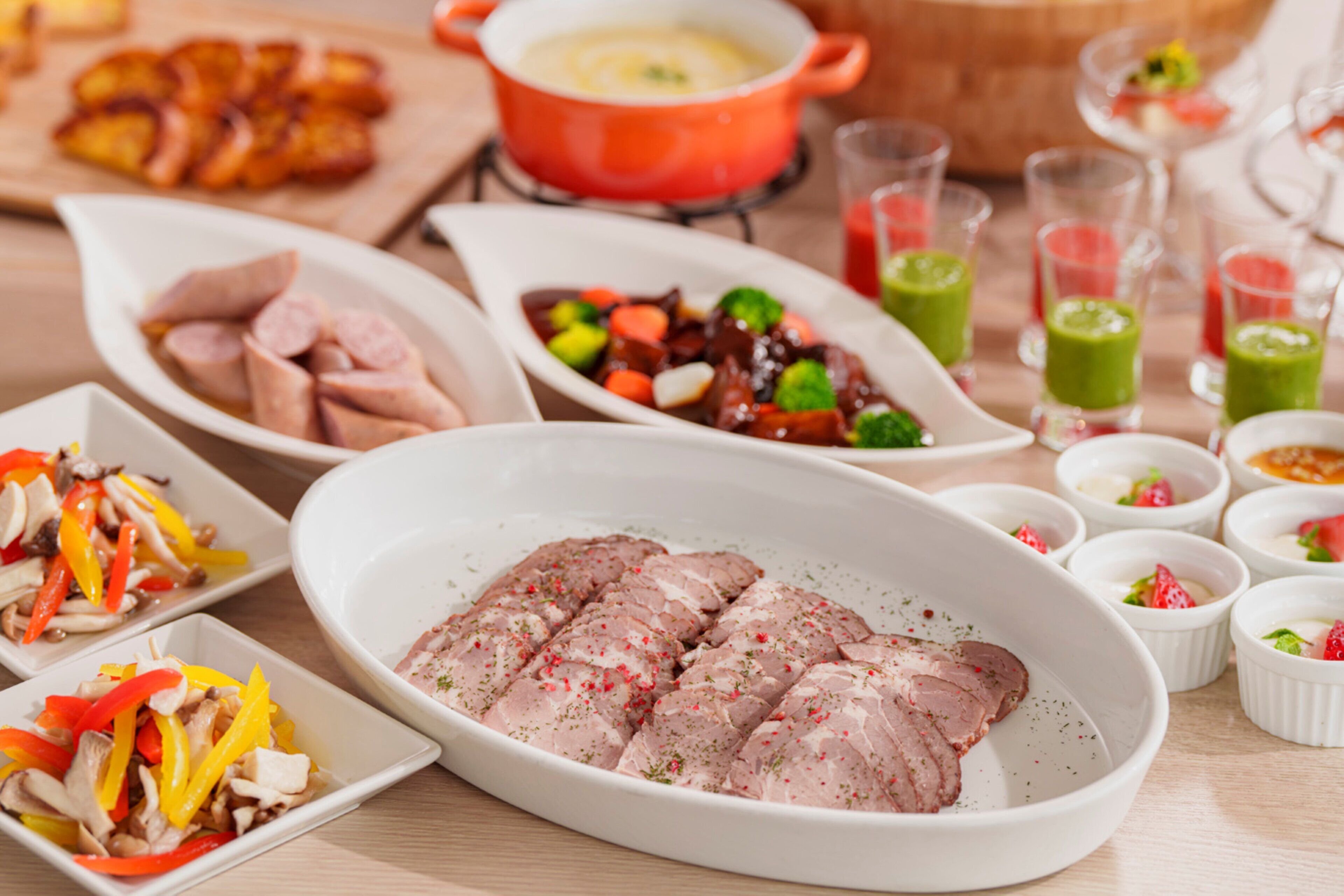 A variety of dishes including sliced meat, vegetables, and a soup pot.