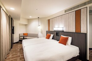 Une chambre d’hôtel avec deux lits, une petite table, un canapé et un téléviseur.