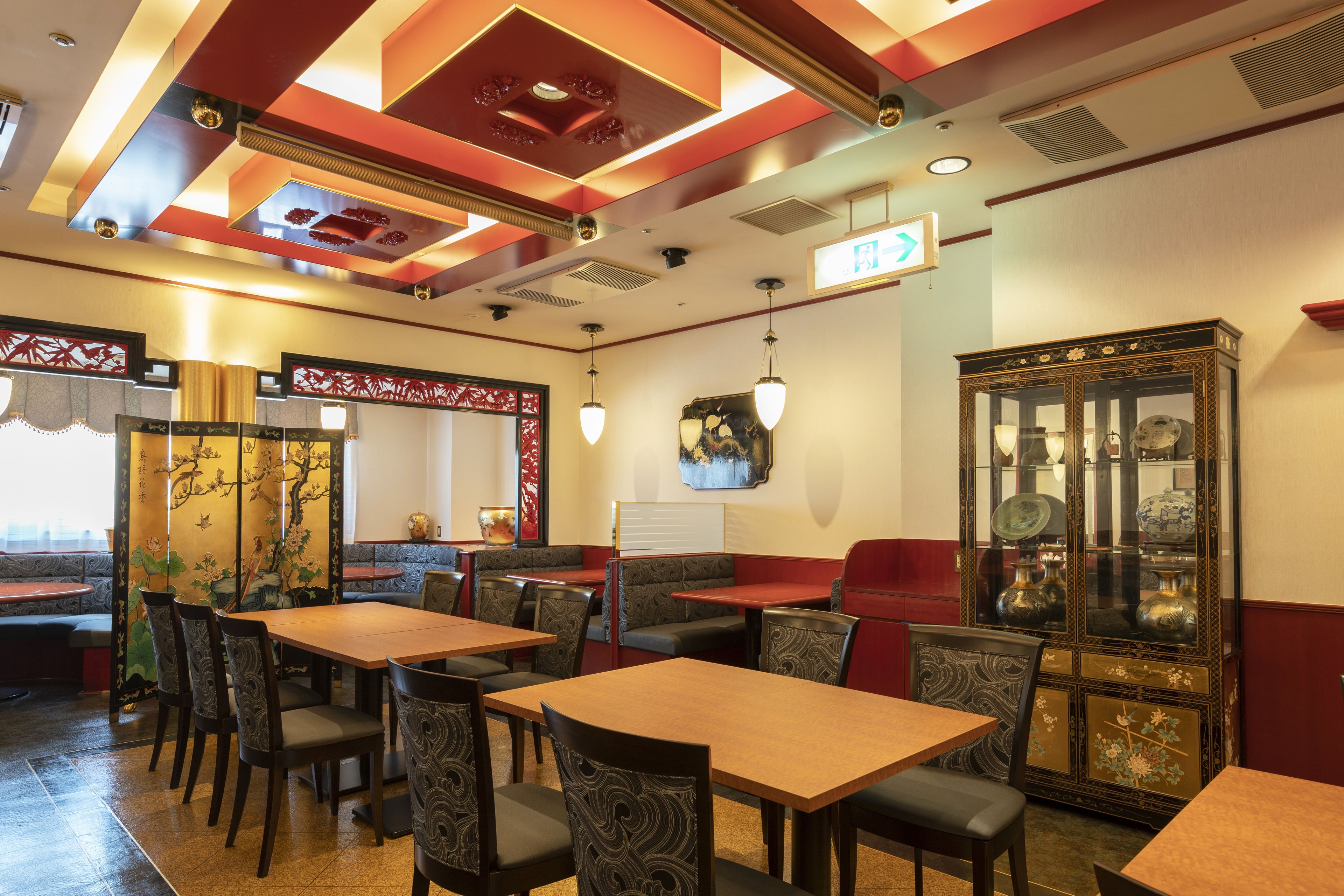 Un restaurante con cabinas y mesas, un techo decorativo y decoración tradicional.