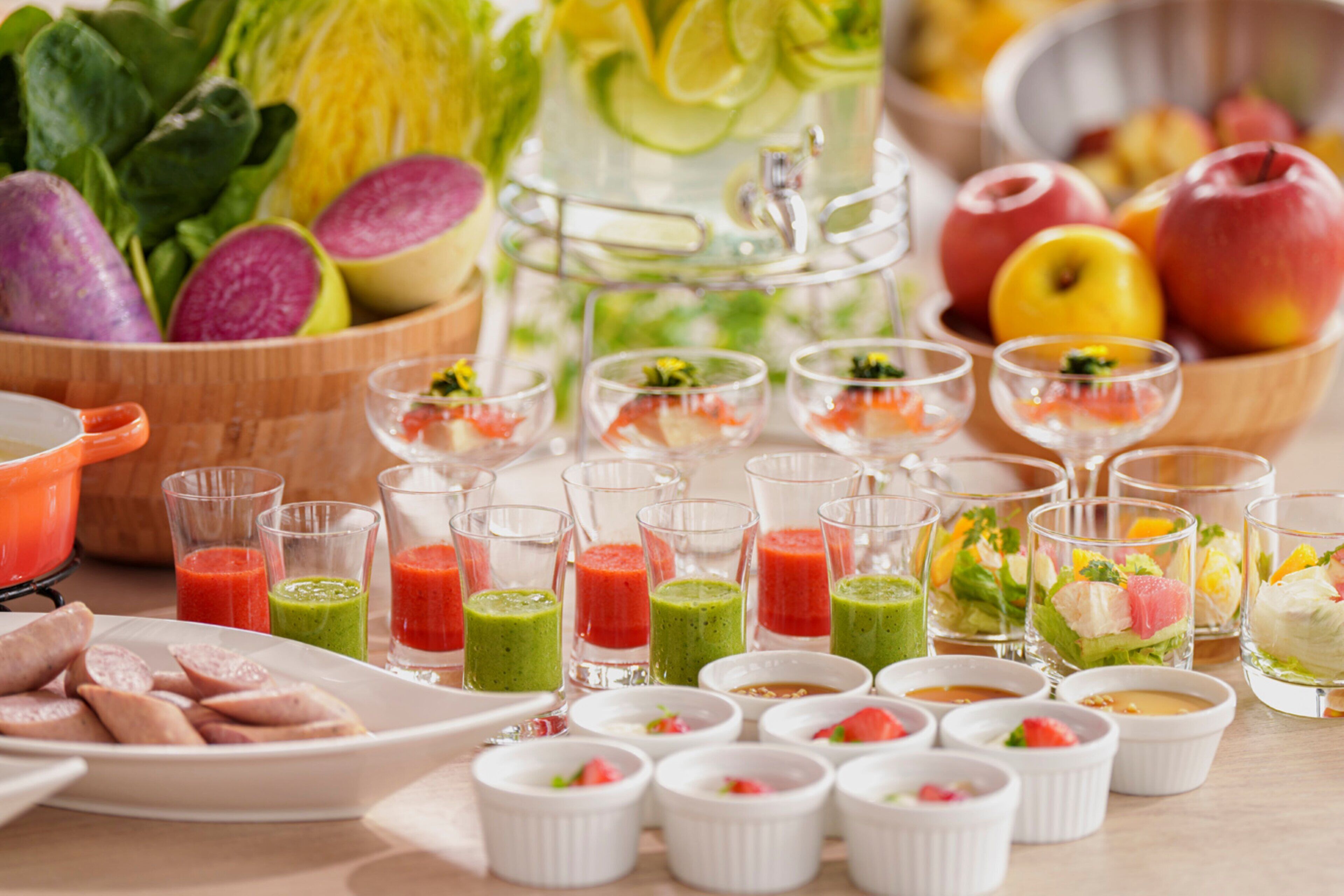 Une variété d’aliments et de boissons, notamment des fruits et des légumes frais, ainsi que des boissons servies dans des verres, sont disposés sur une table.