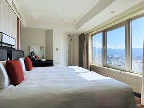 Relax in a spacious room with a large bed, dark desk, and city views.