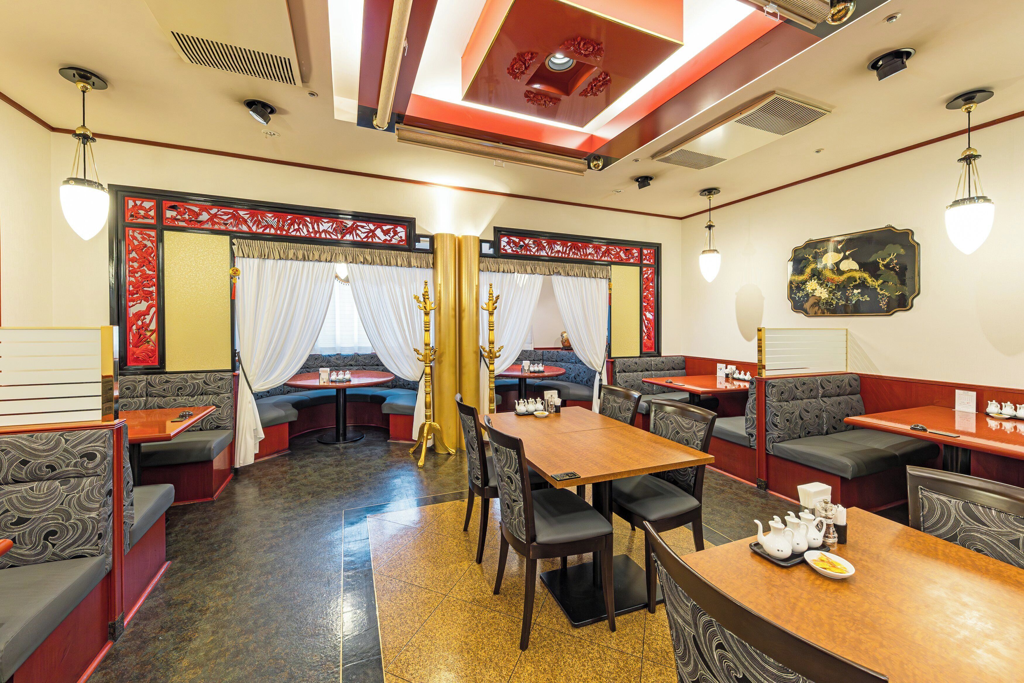 A restaurant with booths and tables, some with cushioned seating.