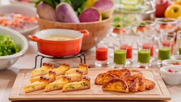 A variety of food items including quiches, a bowl of vegetables, and several glasses of beverages on a wooden table.