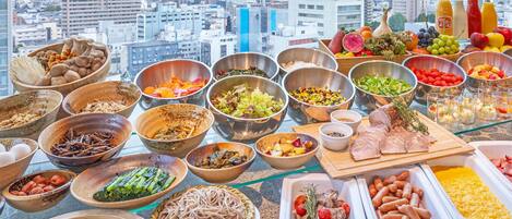 A variety of dishes and food items displayed on a table with a cityscape view in the background.