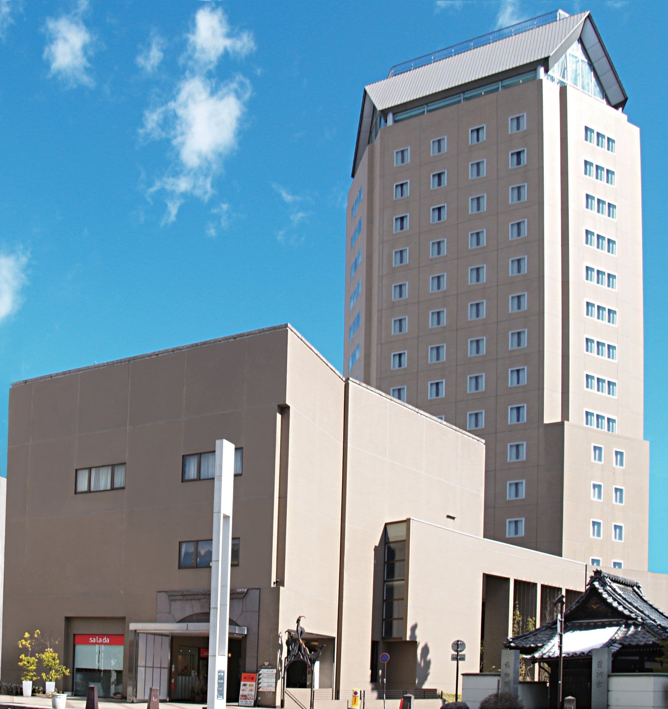 A modern building with a flat facade, multiple windows, and a prominent entrance.