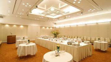 A conference room with multiple tables, a podium, and a ceiling with recessed lighting.