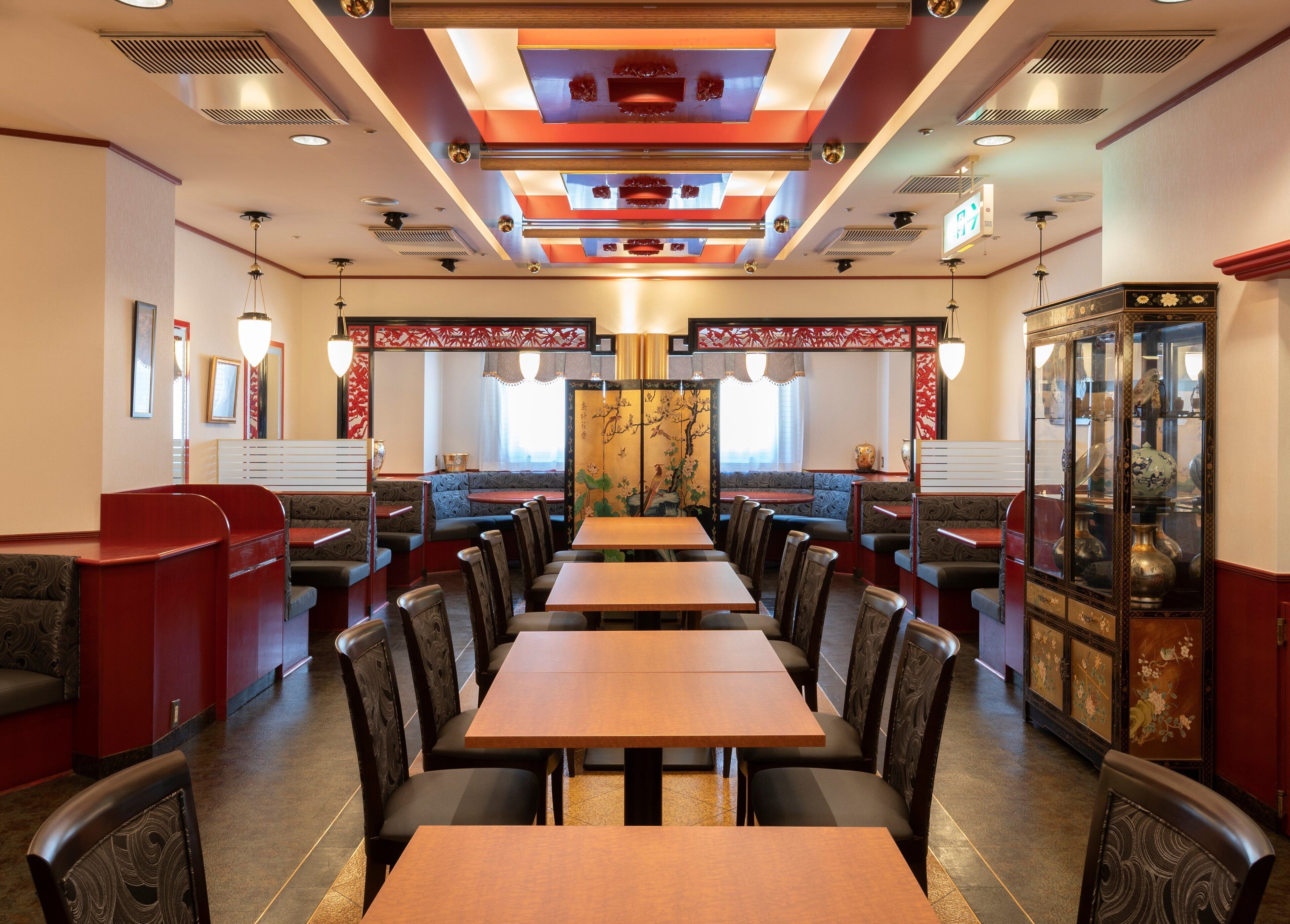 Un restaurante con cabinas y mesas, un techo decorativo y un mueble tradicional con puertas de cristal.