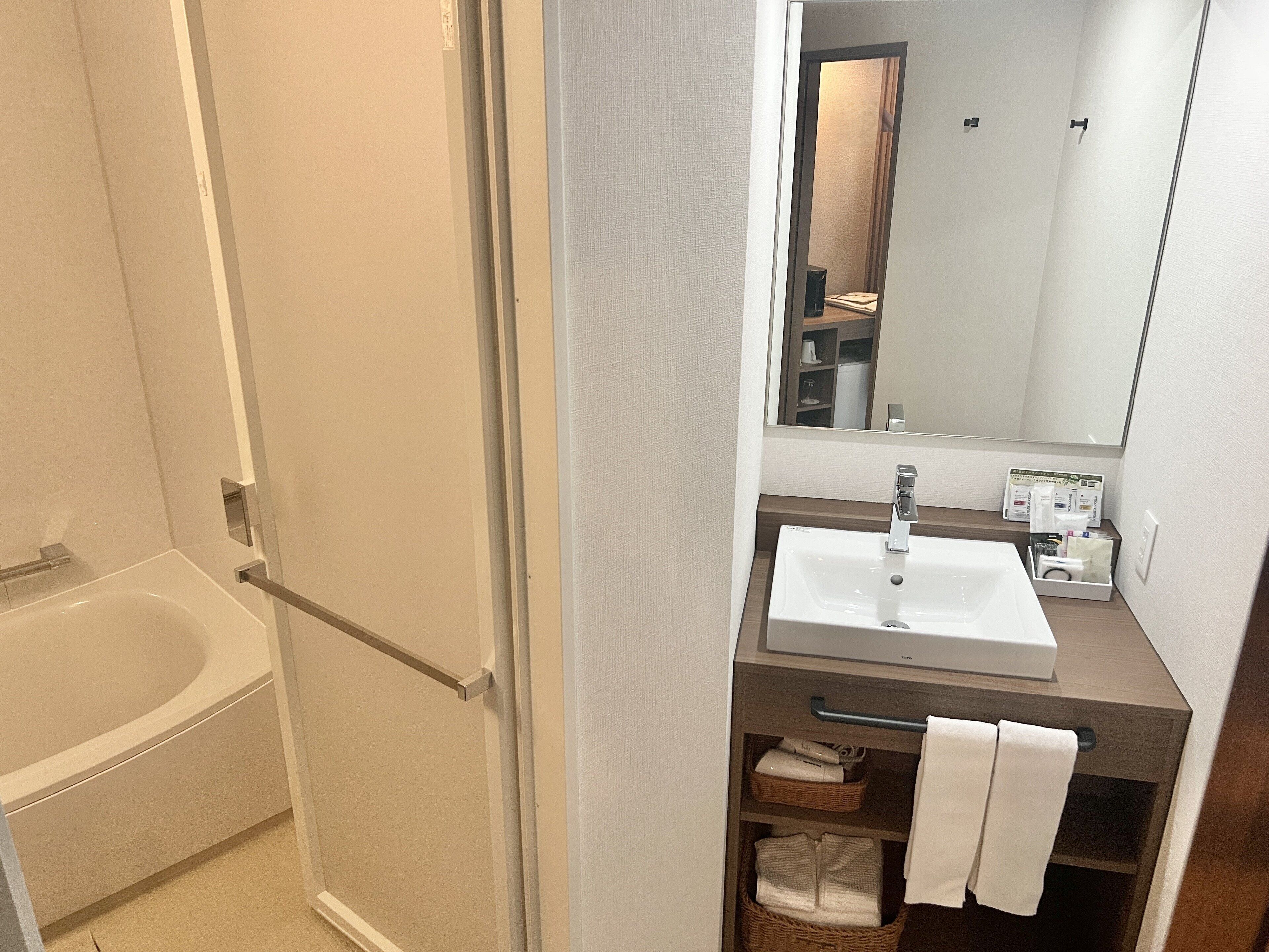 A bathroom with a bathtub, a sink, a mirror, and a towel rack.