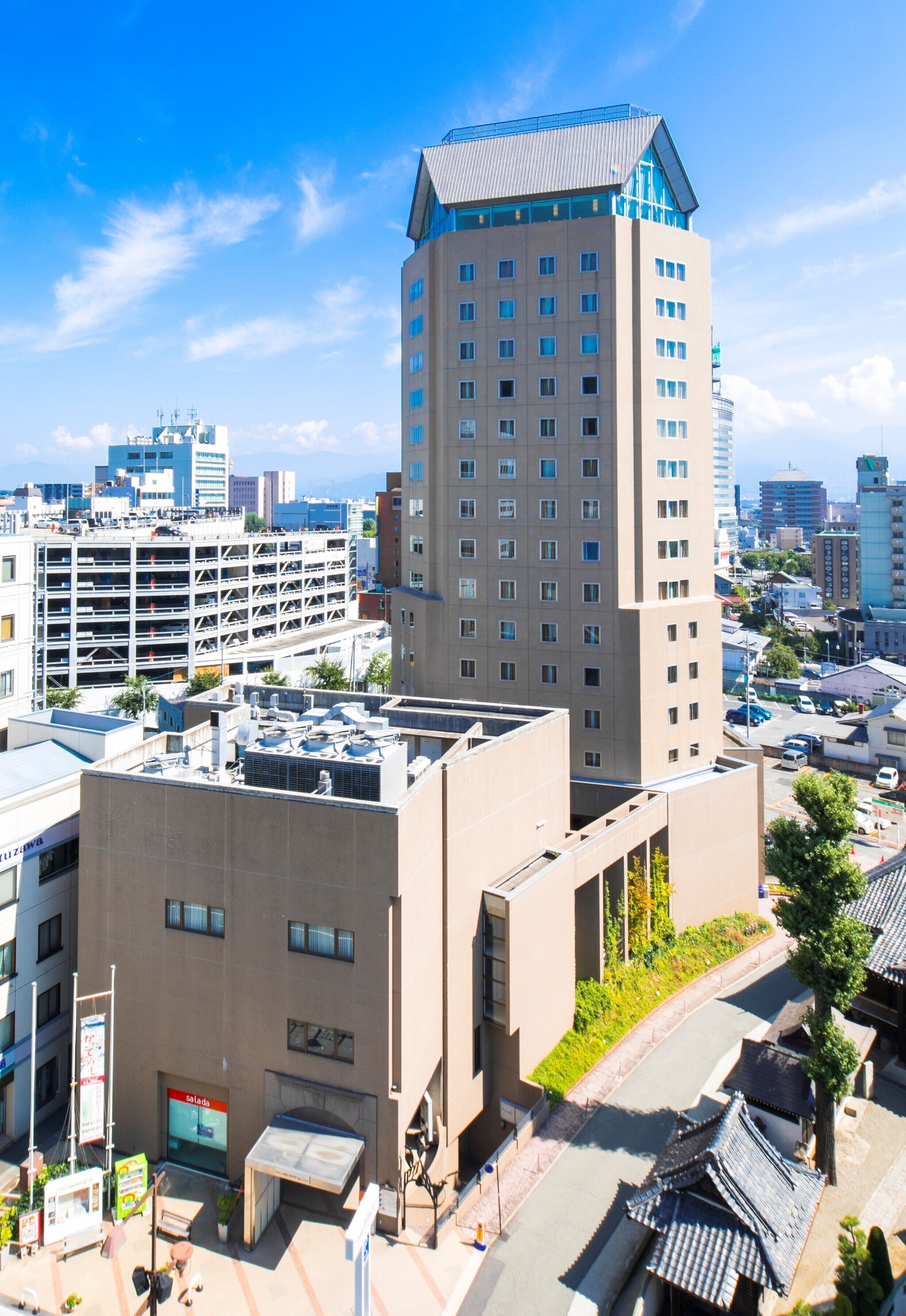 A modern building with multiple floors, a parking garage, and a rooftop with solar panels.