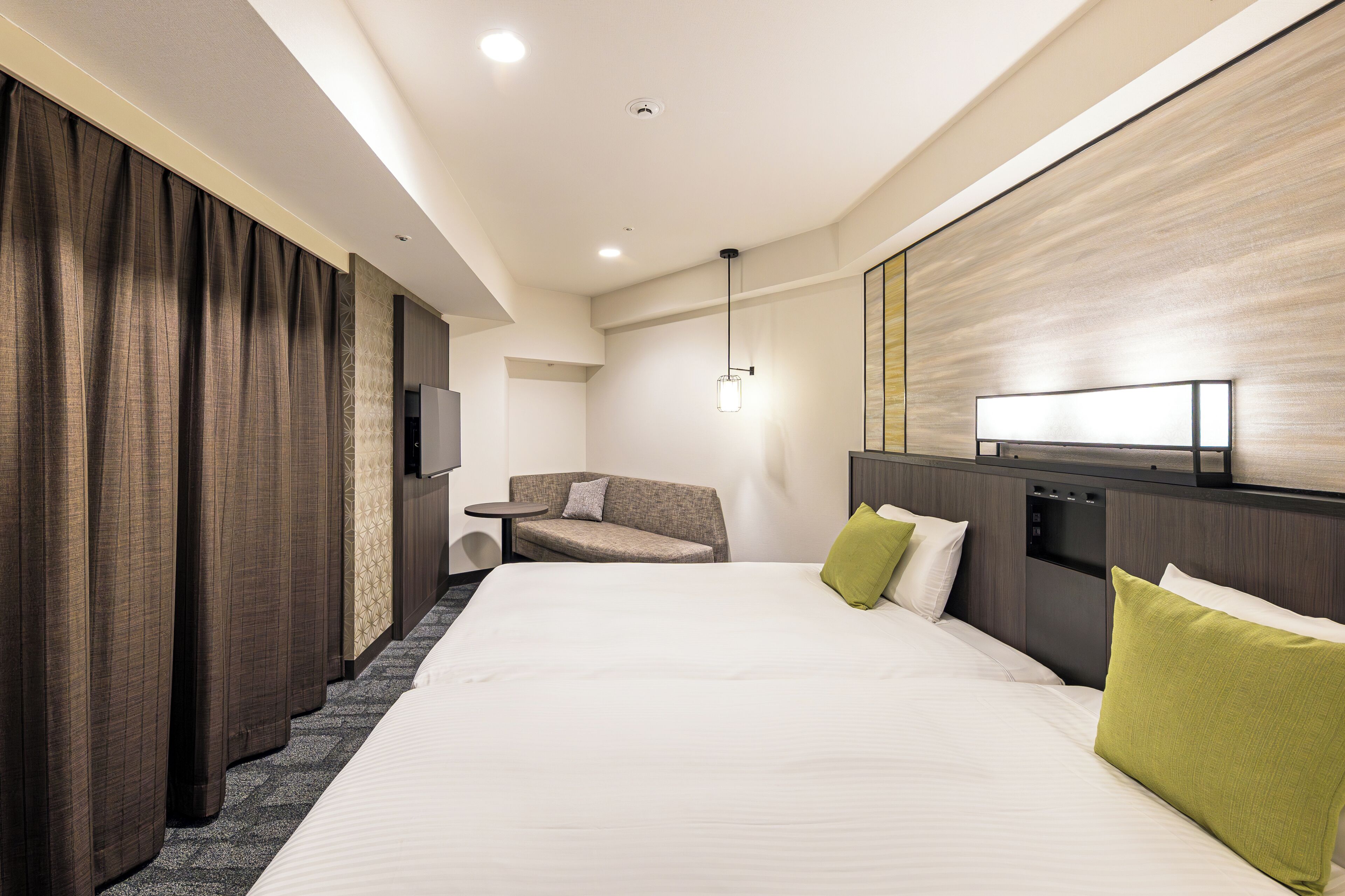 A hotel room with a large bed, a sofa, a small table, and a TV.