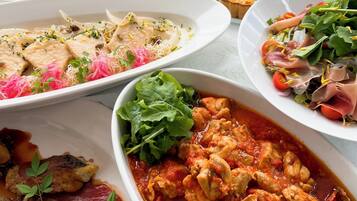 A variety of dishes on a table, including pasta, quiche, and a chicken dish.
