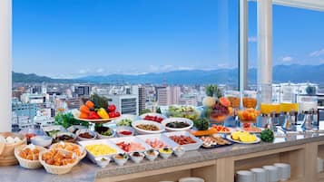 A buffet with a variety of food items and a city view in the background.