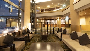A hotel lobby with seating areas, a reception desk, and a view of the entrance.