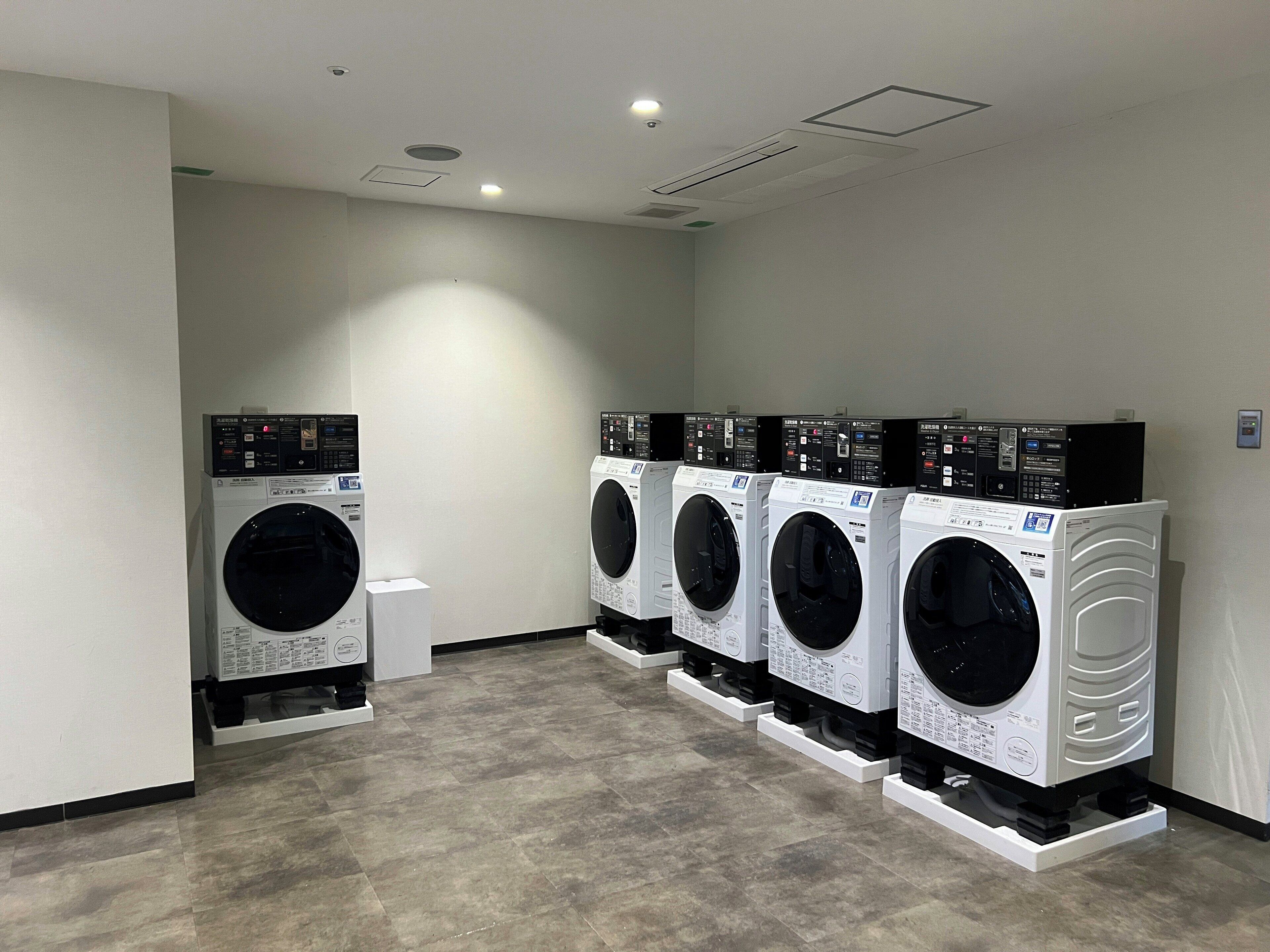 A laundry room with four stacked front-loading washing machines.