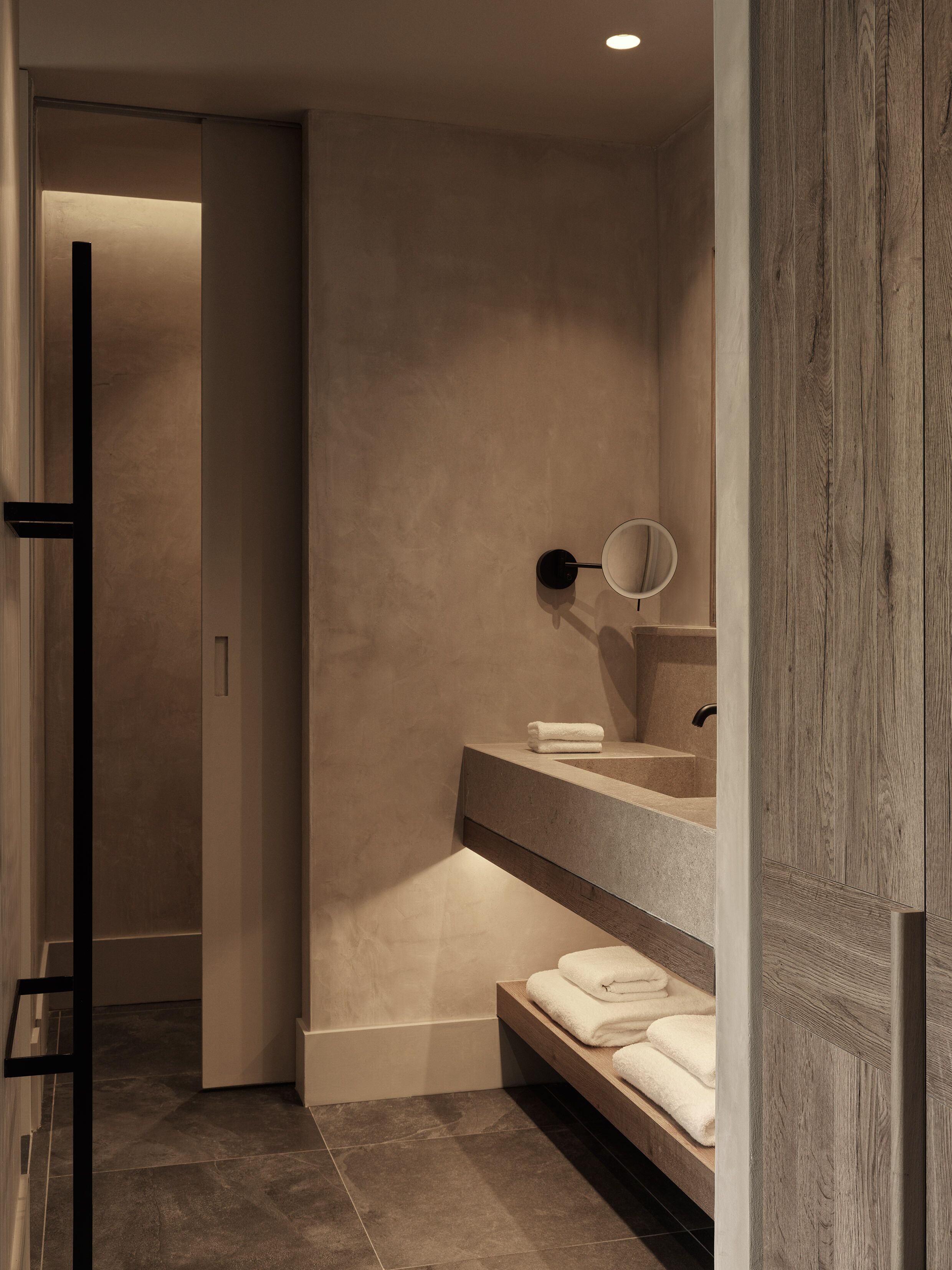 A modern bathroom with a built-in sink, a mirror, and a towel rack.