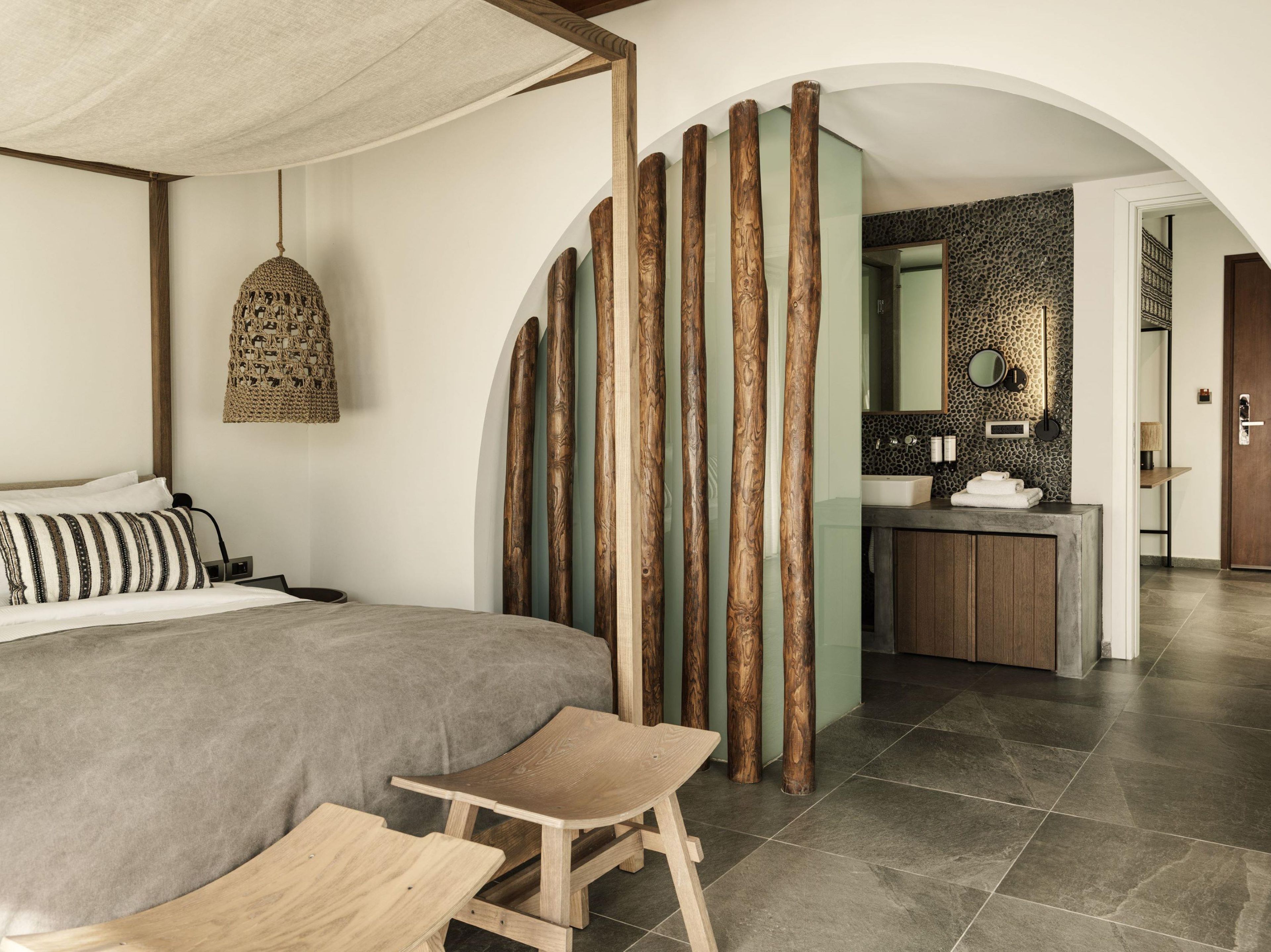 Un dormitorio con cama, mesita de noche, lámpara colgante y vistas al baño.