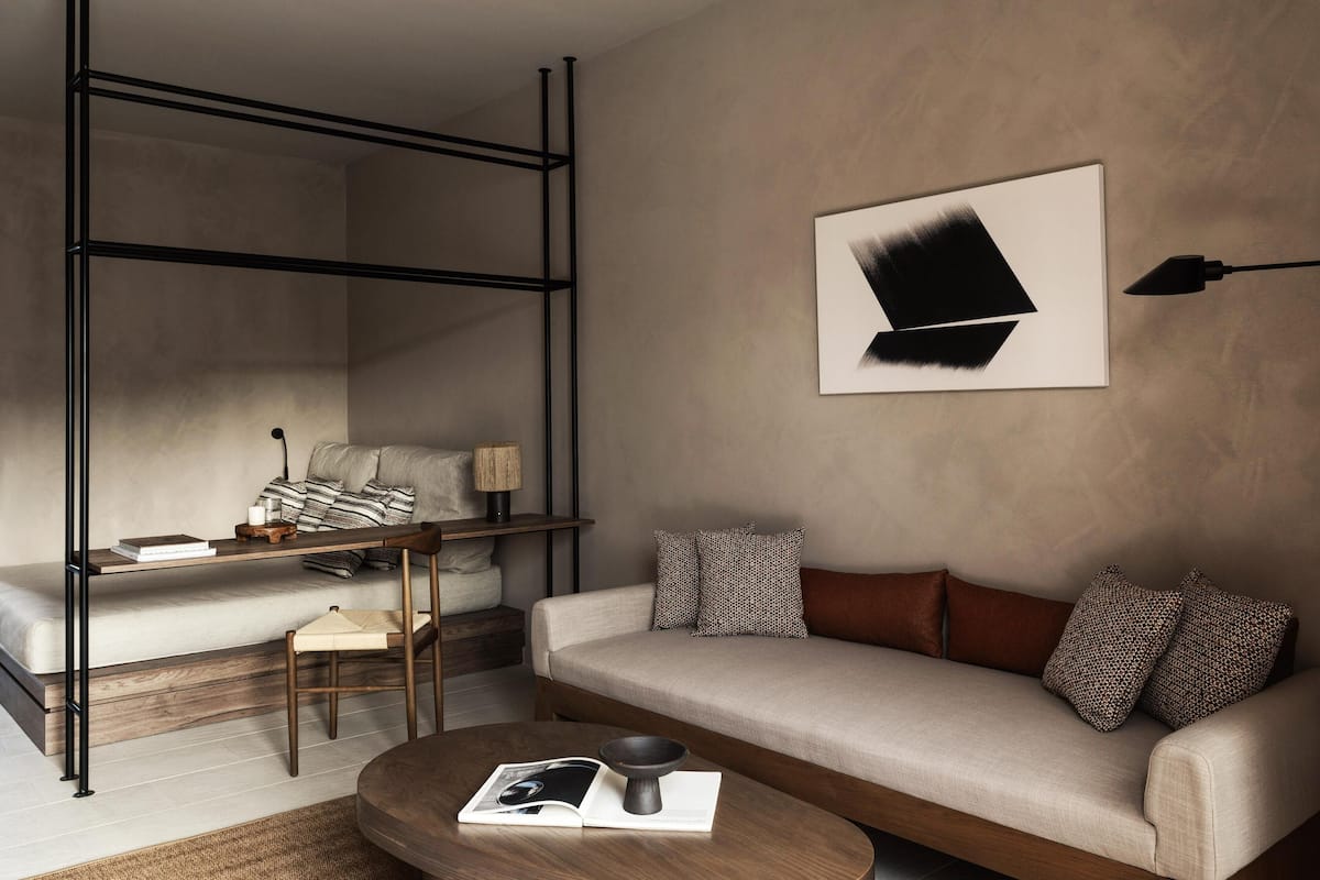 Una habitación moderna con sofá, mesa de centro, mesita auxiliar, lámpara y un cuadro en la pared.