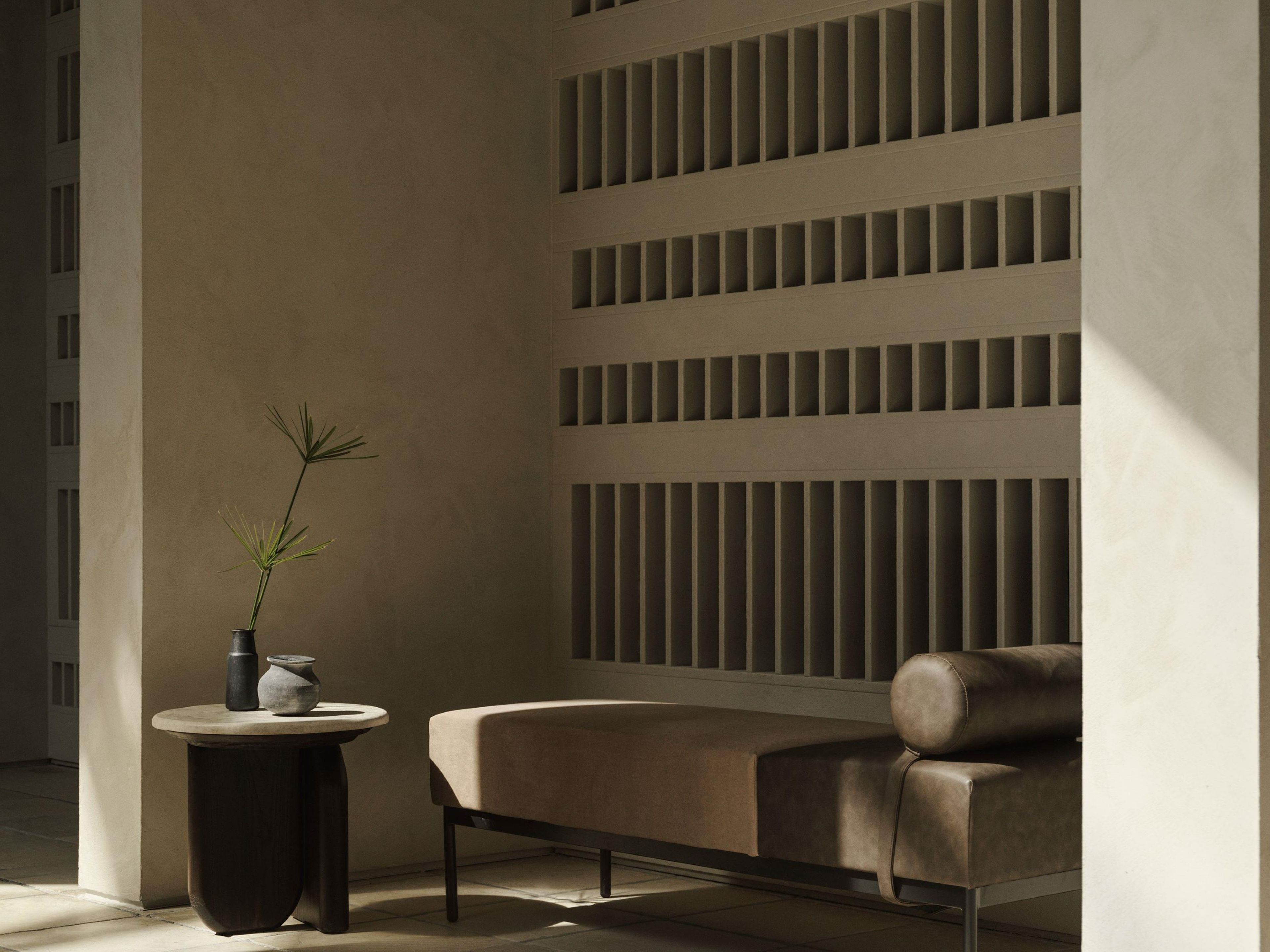 A modern interior with a sofa, a small round table, and a potted plant.