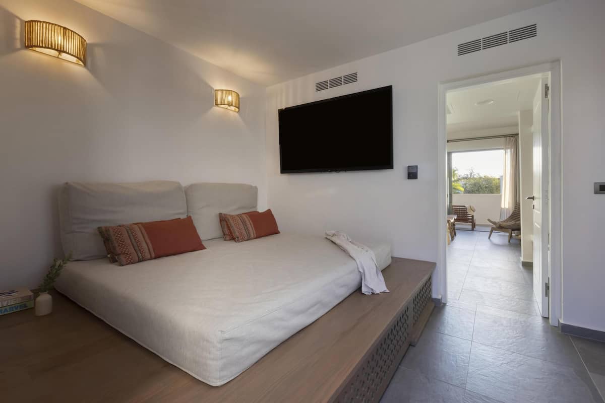 Un dormitorio moderno con una cama grande, un televisor de pantalla plana y un banco empotrado.