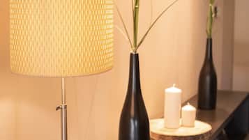 A modern hotel reception area with a floor lamp, vases with flowers, and candles on a wooden console table.