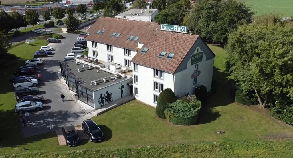 Un hotel con estacionamiento, restaurante y césped verde.