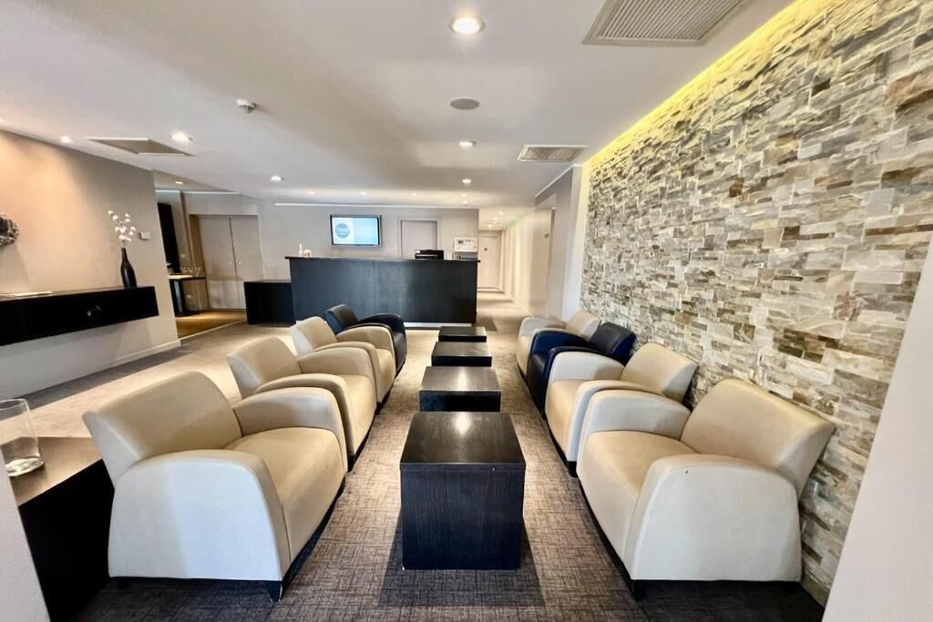 Un espace d’attente moderne avec des canapés, un comptoir d’accueil et un mur en pierre.