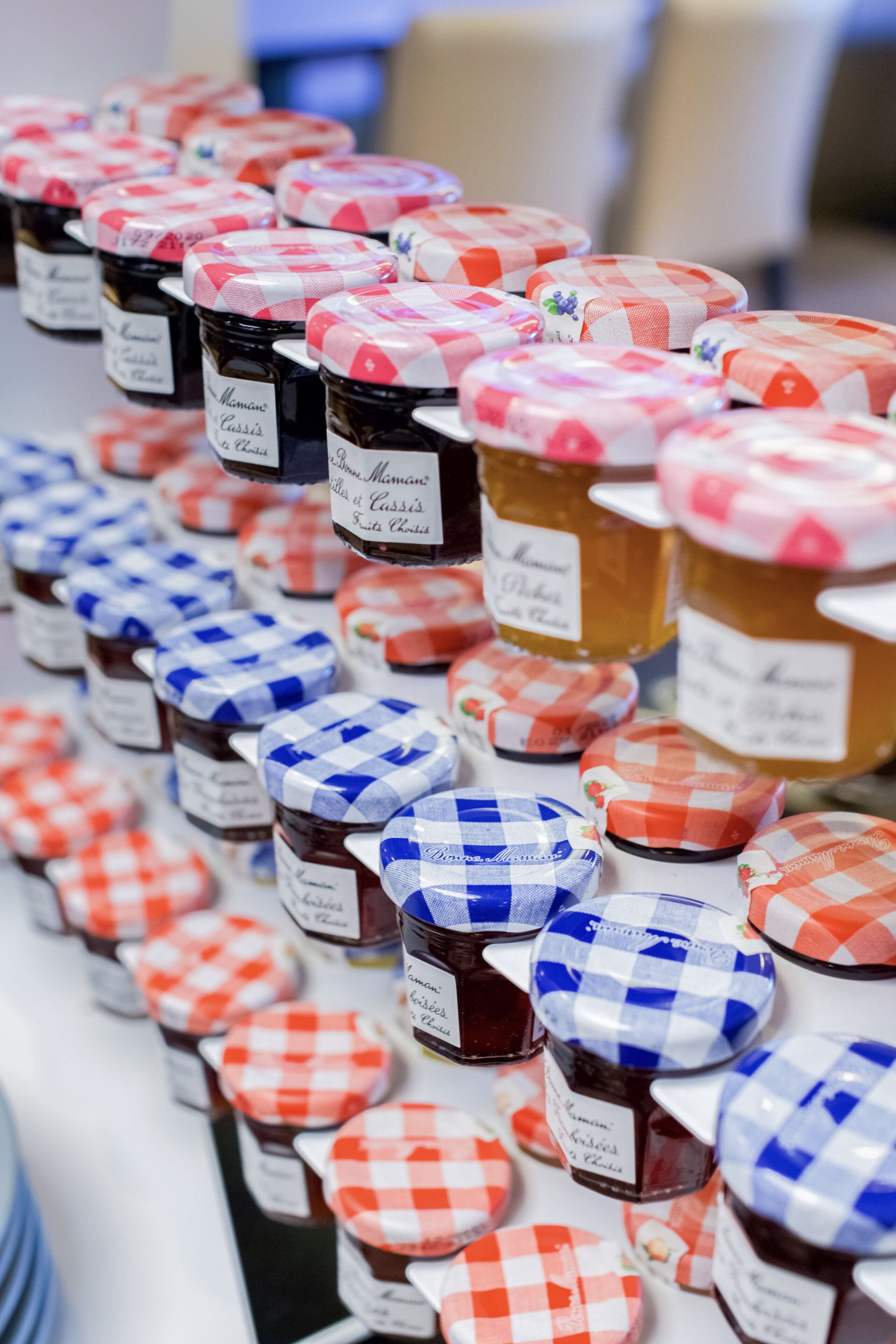 A display of jars with checkered lids and labels, arranged in rows.
