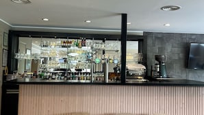 Een bar met krukken, een toonbank met flessen en glazen, en een aan de muur bevestigde televisie.