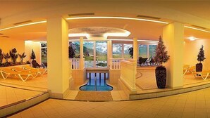 A spacious indoor area with a central pool, surrounded by seating areas and potted plants. - Austria Bellevue (Soelden)